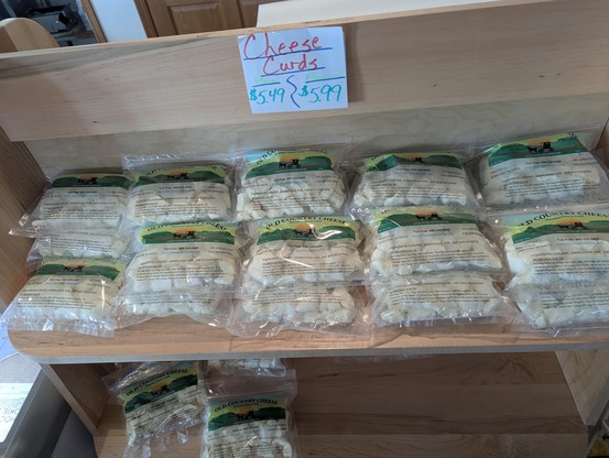 A bunch of fresh cheese curds all stocked up on a shelf, not refridgerated