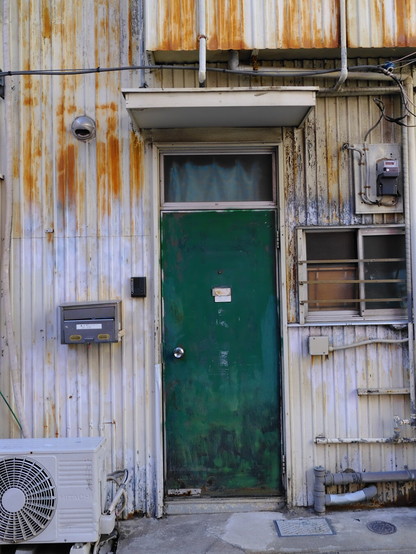 A worn tin building with a green roof, rusting
