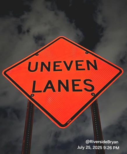 Bright orange traffic sign with spooky night sky as a background. Sign reads: Uneven Lanes.