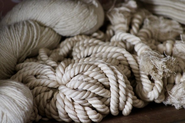 Various bundles of beige rope and yarn are intertwined on a surface. The material appears soft and textured.