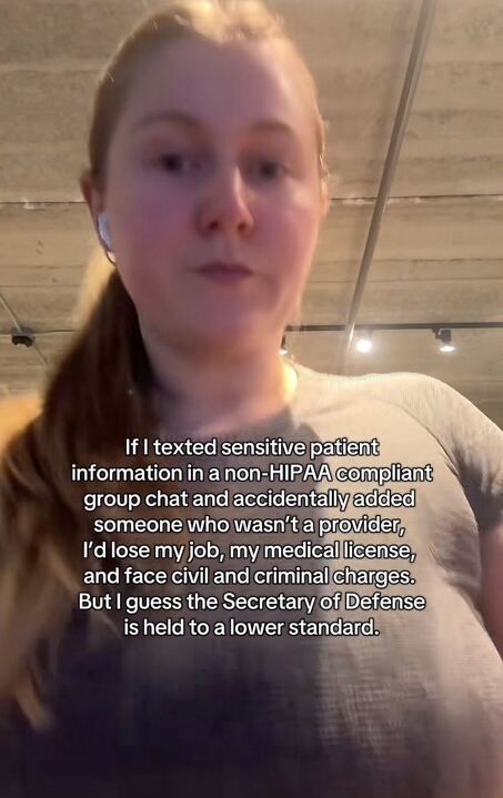 The image shows a person with long blonde hair tied in a ponytail, wearing a light gray shirt and white earbuds. The background appears to be an indoor setting with a ceiling featuring exposed pipes and lights. Overlaid on the image is text that reads: "If I texted sensitive patient information in a non-HIPAA compliant group chat and accidentally added someone who wasn’t a provider, I’d lose my job, my medical license, and face civil and criminal charges. But I guess the Secretary of Defense is held to a lower standard."
